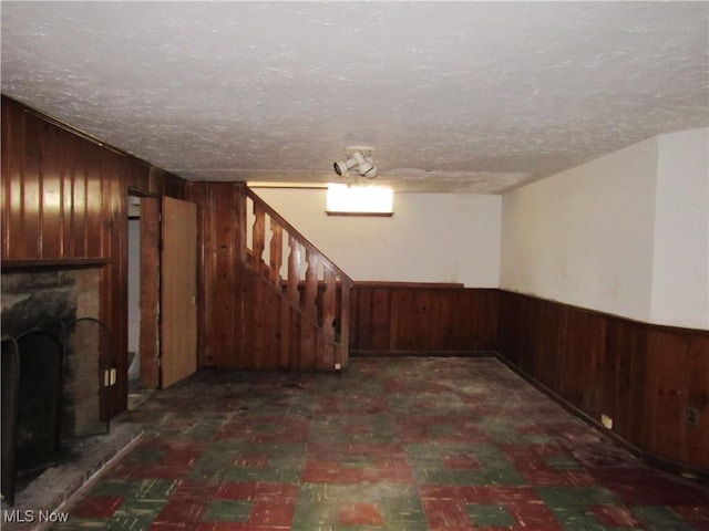 3659 Riedham Rd, Shaker Heights, OH 44120 - finished basement featuring wooden walls, stairway, a textured ceiling, a fireplace with raised hearth, and a wainscoted wall