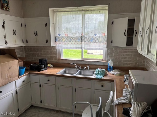 181 5th St NE, Carrollton, OH 44615 - kitchen with a sink, white cabinetry, light countertops, decorative backsplash, and white microwave
