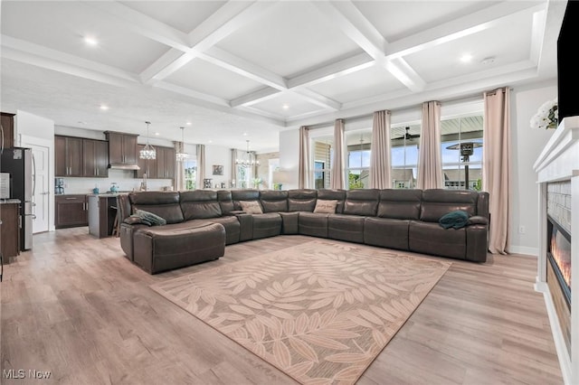 34655 N Legends Way, Grafton, OH 44044 - living area with light wood-style floors, a glass covered fireplace, beamed ceiling, a chandelier, and coffered ceiling