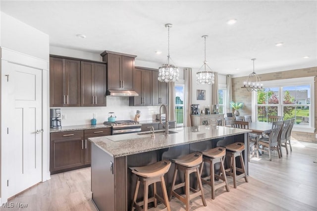 34655 N Legends Way, Grafton, OH 44044 - kitchen with under cabinet range hood, a chandelier, stainless steel range with gas cooktop, light wood-style flooring, and recessed lighting