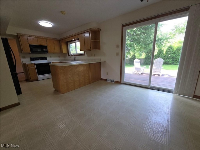 1025 S Ridge Rd, Geneva, OH 44041 - kitchen with white range with electric stovetop, black microwave, a peninsula, baseboards, and light countertops