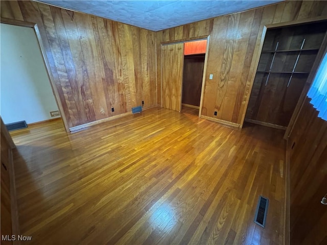 158 Main St, Rayland, OH 43943 - unfurnished bedroom featuring wood finished floors, wood walls, and multiple closets
