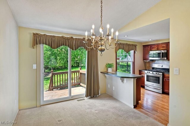 2610 Norton Rd, Stow, OH 44224 - kitchen featuring appliances with stainless steel finishes, dark countertops, a chandelier, decorative backsplash, and vaulted ceiling