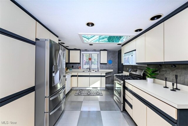 552 Saunders Ave, Akron, OH 44319 - kitchen featuring stainless steel appliances, a skylight, light countertops, white cabinetry, and recessed lighting