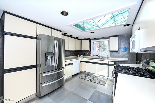 552 Saunders Ave, Akron, OH 44319 - kitchen with stainless steel appliances, a skylight, white cabinetry, light countertops, and recessed lighting