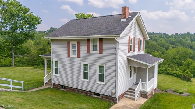 51300 Wegee Rd, Bellaire, OH 43906 - view of front of house with a chimney, roof with shingles, a front yard, and a forest view