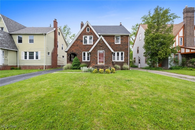 3497 Raymont Blvd, University Heights, OH 44118 - tudor house featuring a front lawn, asphalt driveway, and brick siding