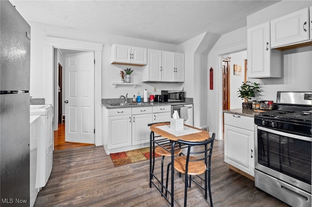 14520 Bayes Ave, Lakewood, OH 44107 - kitchen featuring stainless steel appliances, washer and dryer, dark wood-style floors, a sink, and a textured ceiling