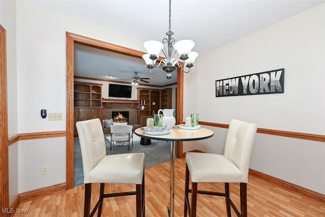 452 Herbert Rd, Akron, OH 44312 - dining room featuring wood finished floors, a brick fireplace, ceiling fan, a chandelier, and baseboards