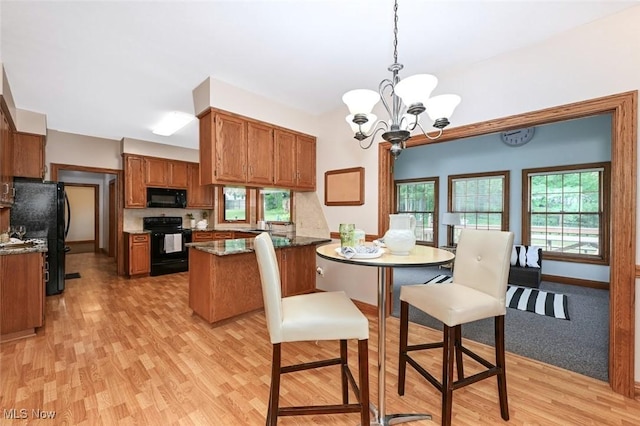 452 Herbert Rd, Akron, OH 44312 - kitchen featuring black appliances, brown cabinetry, light wood finished floors, hanging light fixtures, and a chandelier