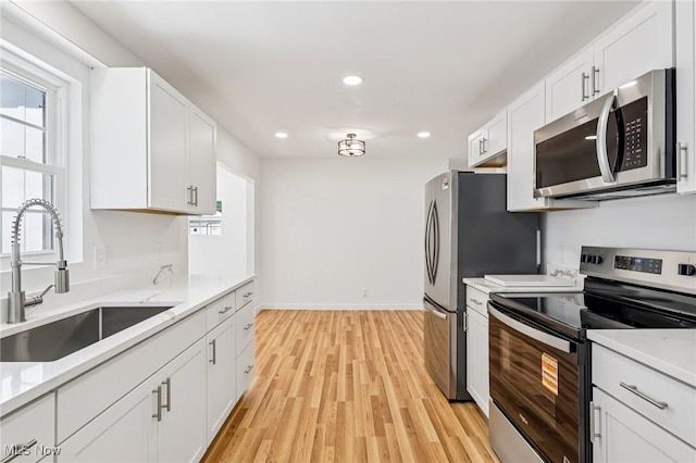 178 Lindsey Rd, Munroe Falls, OH 44262 - kitchen featuring stainless steel appliances, a sink, white cabinets, light wood-style flooring, and light countertops