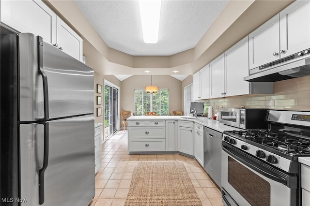 10378 N Pond Ln N Unit 2, Twinsburg, OH 44087 - kitchen featuring appliances with stainless steel finishes, a peninsula, under cabinet range hood, white cabinetry, and a textured ceiling