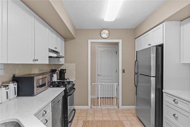10378 N Pond Ln N Unit 2, Twinsburg, OH 44087 - kitchen featuring stainless steel appliances, under cabinet range hood, white cabinets, decorative backsplash, and baseboards