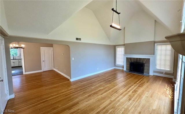 19627 Winslow Rd, Shaker Heights, OH 44122 - unfurnished living room with a chandelier, wood finished floors, high vaulted ceiling, a tile fireplace, and baseboards