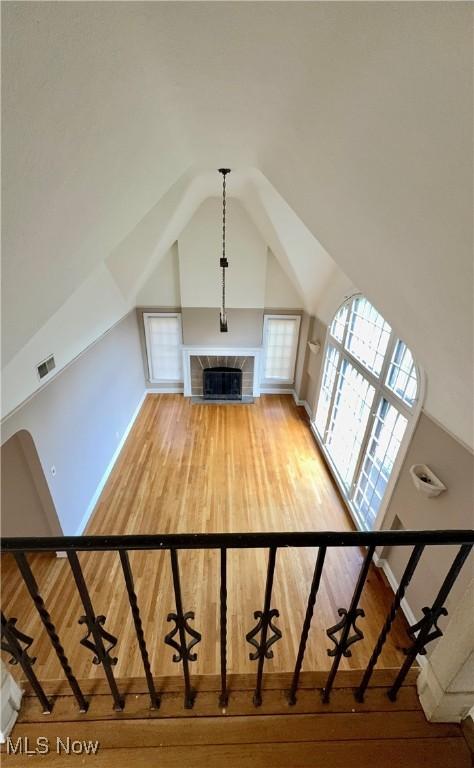 19627 Winslow Rd, Shaker Heights, OH 44122 - unfurnished living room with light wood-style flooring, lofted ceiling, a tiled fireplace, and baseboards