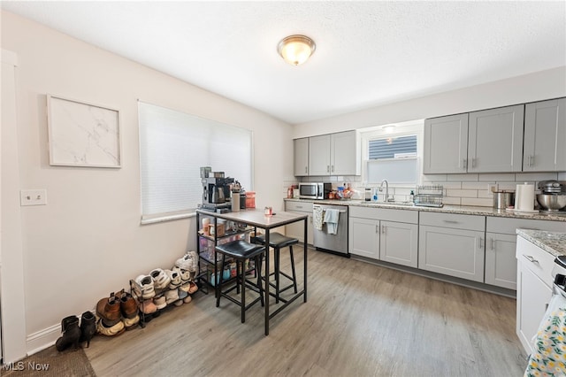 3357-3359 Rocky River Dr, Cleveland, OH 44111 - kitchen with appliances with stainless steel finishes, gray cabinets, a sink, and light wood finished floors