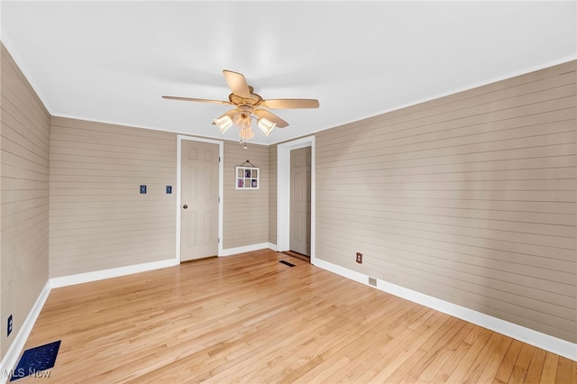 23789 Snell Rd, Columbia Station, OH 44028 - unfurnished room featuring baseboards, a ceiling fan, light wood-type flooring, and wooden walls