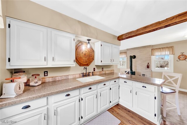 23789 Snell Rd, Columbia Station, OH 44028 - kitchen featuring a sink, a peninsula, white cabinetry, a wood stove, and light wood-type flooring