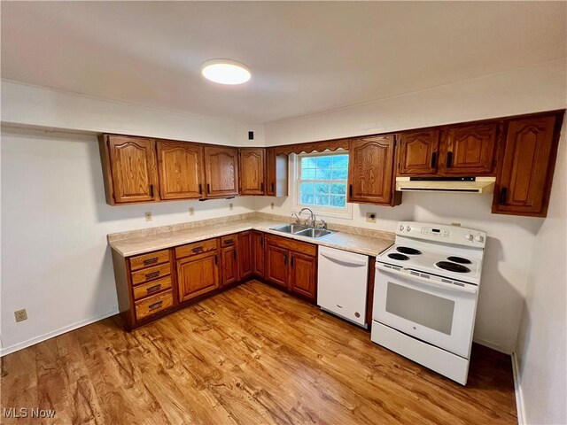 818 2nd St, Brilliant, OH 43913 - kitchen with white appliances, under cabinet range hood, a sink, brown cabinetry, and light countertops