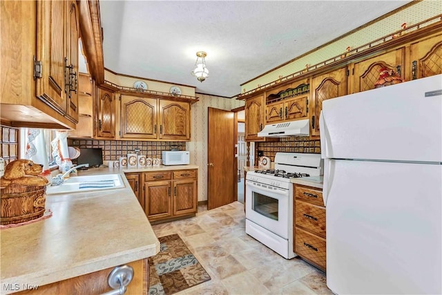 3622 Valacamp Ave SE, Warren, OH 44484 - kitchen with white appliances, under cabinet range hood, brown cabinetry, a sink, and light countertops