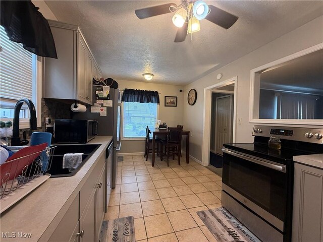 20007 Sunset Dr, Warrensville Heights, OH 44122 - kitchen with electric stove, light countertops, ceiling fan, gray cabinetry, and light tile patterned floors