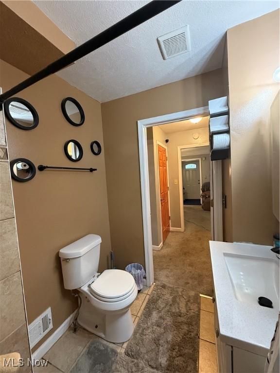 20007 Sunset Dr, Warrensville Heights, OH 44122 - bathroom featuring toilet, vanity, baseboards, a textured ceiling, and tile patterned floors
