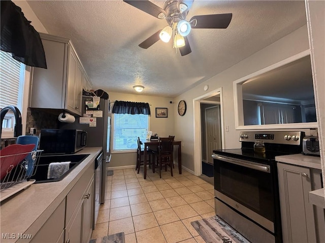 20007 Sunset Dr, Warrensville Heights, OH 44122 - kitchen featuring appliances with stainless steel finishes, a textured ceiling, a ceiling fan, light countertops, and light tile patterned floors