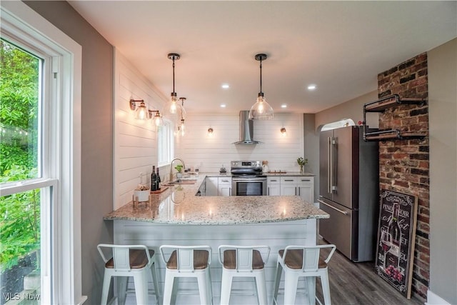 680 Isle View Dr, Akron, OH 44319 - kitchen with appliances with stainless steel finishes, wall chimney exhaust hood, a peninsula, light stone countertops, and dark wood-style floors