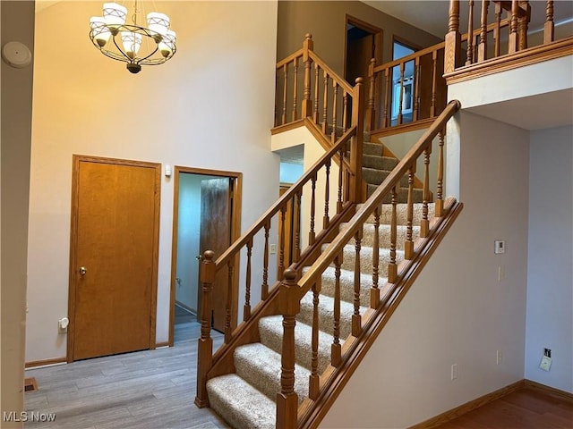 7687 Galena St NW, Massillon, OH 44646 - stairway featuring wood finished floors, baseboards, a towering ceiling, and a chandelier