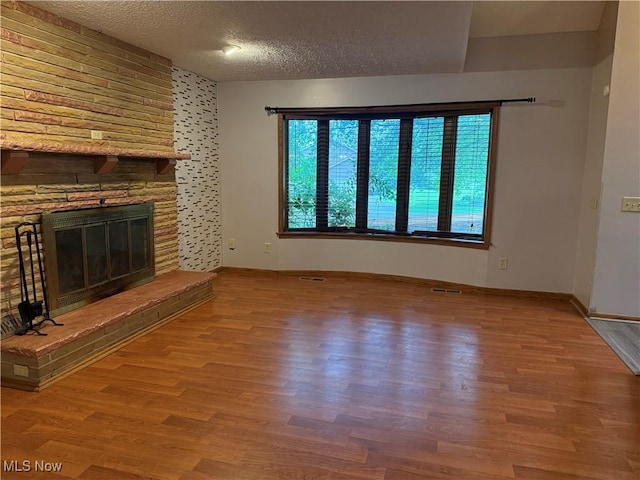 7687 Galena St NW, Massillon, OH 44646 - unfurnished living room with wood finished floors, a textured ceiling, a fireplace, and baseboards