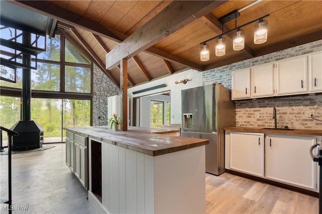 6226 Mayburn Barclay Rd, Kinsman, OH 44428 - kitchen featuring butcher block countertops, stainless steel fridge with ice dispenser, wooden ceiling with exposed beams, a sink, and a wood stove