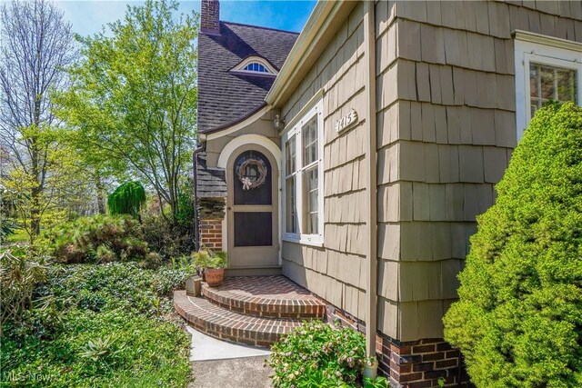 1415 Inwood Rd, Alliance, OH 44601 - view of exterior entry with a shingled roof and a chimney
