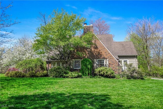 1415 Inwood Rd, Alliance, OH 44601 - tudor-style house with a front lawn, a chimney, and brick siding
