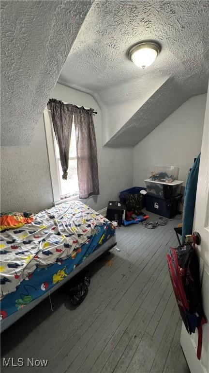 3415 E 114th St, Cleveland, OH 44104 - bedroom featuring a textured ceiling, lofted ceiling, and wood-type flooring