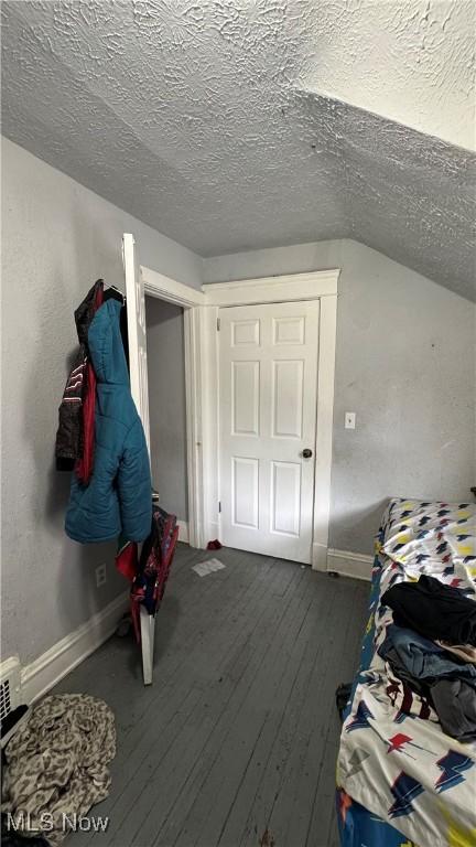 3415 E 114th St, Cleveland, OH 44104 - bedroom with a textured ceiling, baseboards, dark wood-type flooring, and lofted ceiling