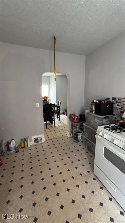 3415 E 114th St, Cleveland, OH 44104 - kitchen with white gas stove, arched walkways, and a textured ceiling