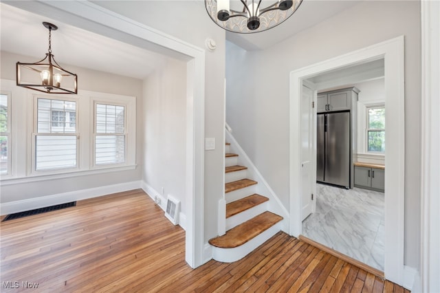 3020 E Derbyshire Rd, Cleveland Heights, OH 44118 - stairs with a chandelier, wood-type flooring, and baseboards