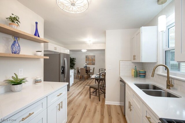 3762 Covington Rd, South Euclid, OH 44121 - kitchen with a sink, appliances with stainless steel finishes, light wood-type flooring, decorative backsplash, and white cabinets