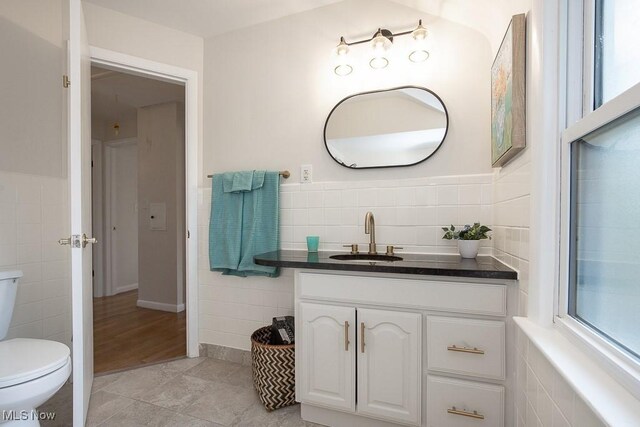 3762 Covington Rd, South Euclid, OH 44121 - bathroom with tile walls, toilet, vanity, tile patterned floors, and plenty of natural light