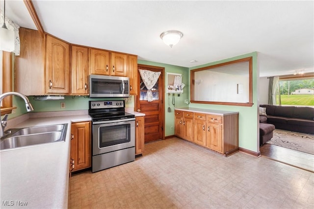 22938 US Route 30, Minerva, OH 44657 - kitchen with appliances with stainless steel finishes, a sink, light countertops, light flooring, and brown cabinetry