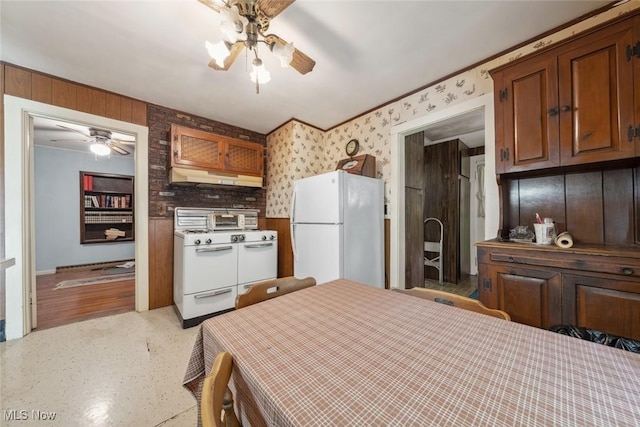 7100 Barton Rd, North Olmsted, OH 44070 - kitchen featuring white appliances, a ceiling fan, under cabinet range hood, wallpapered walls, and brown cabinetry