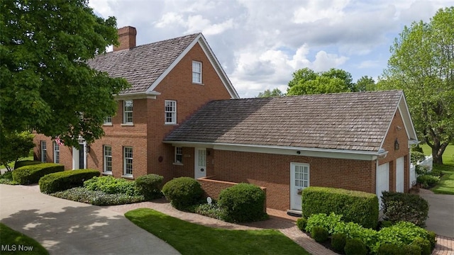 195 W 5th St, Zoar, OH 44622 - view of front of home featuring brick siding, a chimney, concrete driveway, and an attached garage