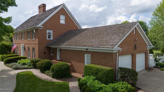 195 W 5th St, Zoar, OH 44622 - view of side of home featuring brick siding, a chimney, and a garage