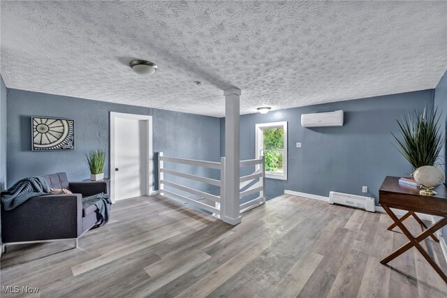 225 E Bergey St, Wadsworth, OH 44281 - living area with an AC wall unit, wood finished floors, a textured ceiling, decorative columns, and a baseboard radiator