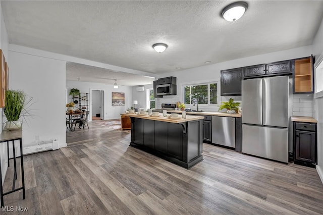 225 E Bergey St, Wadsworth, OH 44281 - kitchen featuring appliances with stainless steel finishes, a textured ceiling, light wood-type flooring, tasteful backsplash, and a kitchen bar