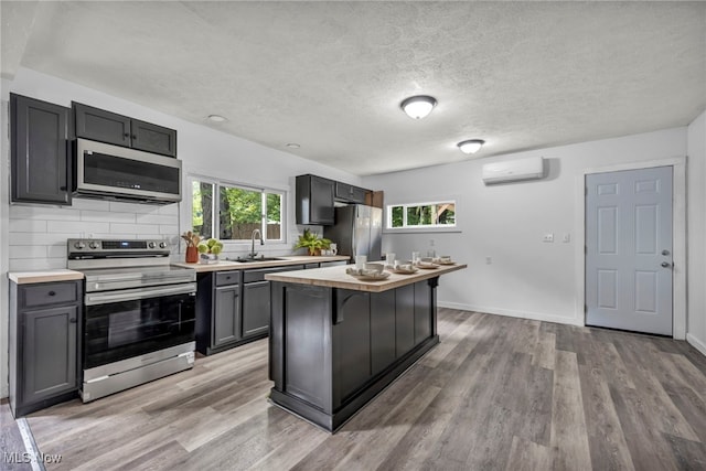 225 E Bergey St, Wadsworth, OH 44281 - kitchen featuring stainless steel appliances, a wall mounted air conditioner, light countertops, light wood-style flooring, and a textured ceiling