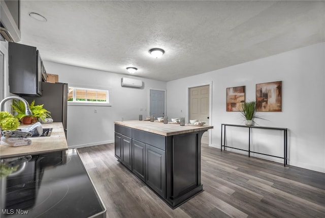 225 E Bergey St, Wadsworth, OH 44281 - kitchen with wood counters, a wall mounted air conditioner, dark wood-style flooring, a center island, and a textured ceiling