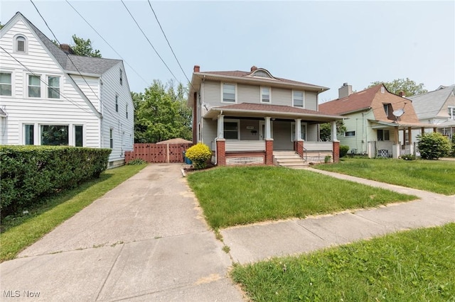 1222 W 6th St, Lorain, OH 44052 - american foursquare style home with covered porch, driveway, a front lawn, and a gate