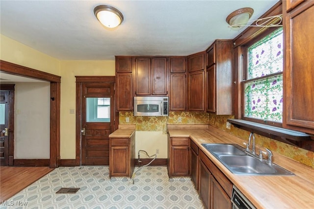 1222 W 6th St, Lorain, OH 44052 - kitchen featuring stainless steel microwave, light countertops, a sink, decorative backsplash, and baseboards