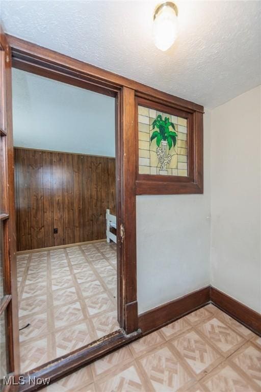 1222 W 6th St, Lorain, OH 44052 - entryway with light flooring, wood walls, baseboards, and a textured ceiling